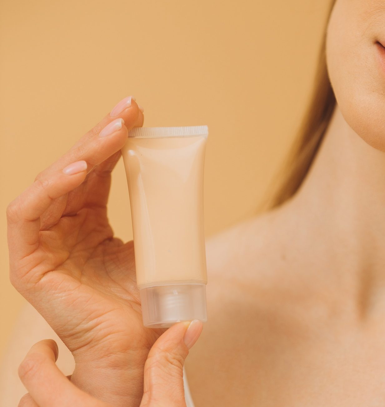 A woman is holding a tube with cosmetic cream. Close up.