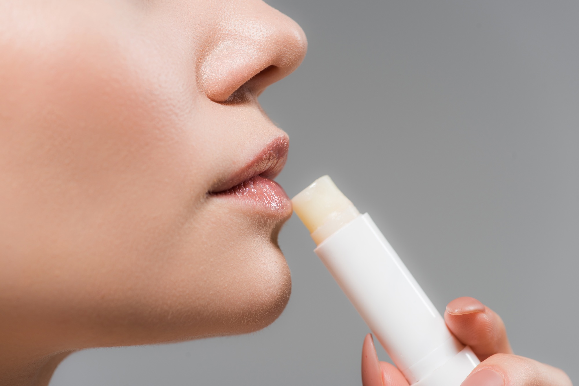 cropped view of woman holding lip balm isolated on grey