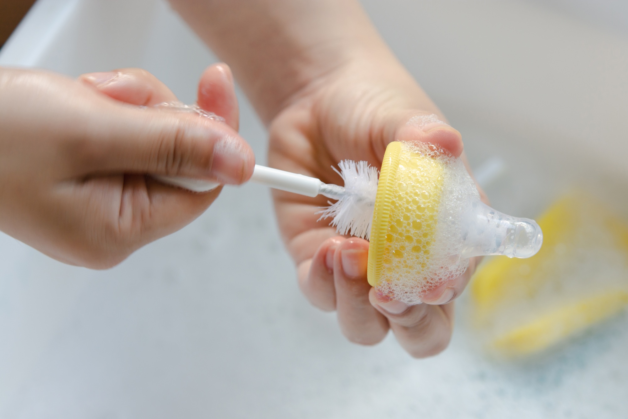 Washing baby nipples. Mother's hand washing the baby nipples