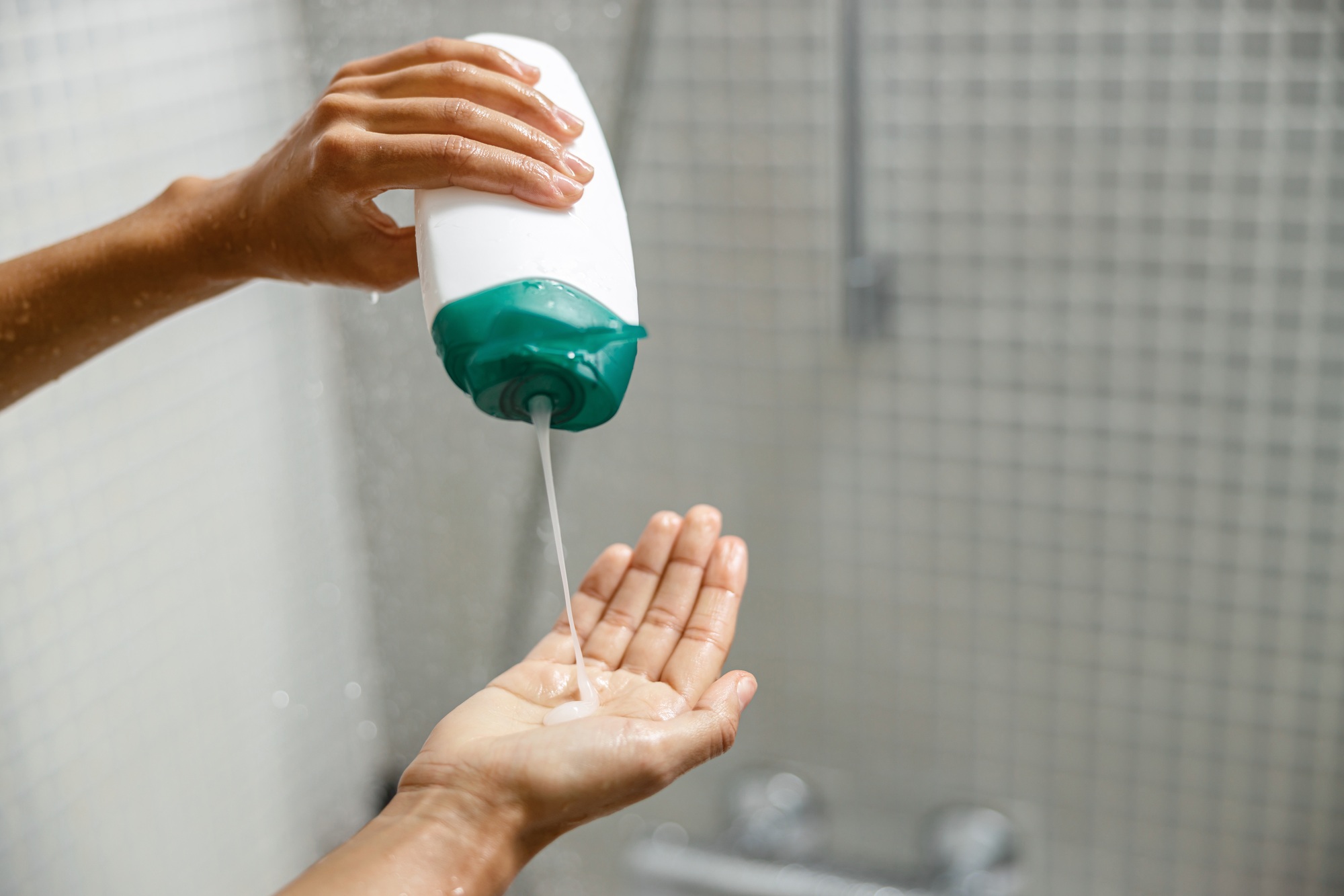 Woman pouring shower gel on her hand when taking shower. Hygiene concept